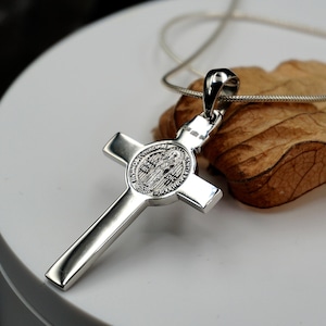 May include: Silver St. Christopher pendant necklace with a cross design and a round medal featuring a religious image.