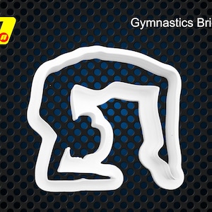 Może przedstawiać: Biała plastikowa foremka do ciasteczek w kształcie mostu gimnastycznego. Foremka ma kształt gimnastyczki wykonującej mostek.