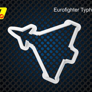 Può includere: Tagliapasta in plastica bianca a forma di aereo da combattimento Eurofighter Typhoon. Il tagliapasta è su uno sfondo nero e blu.