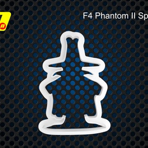 Op de afbeelding: Witte plastic koekjesvormer in de vorm van een F4 Phantom II gevechtsvliegtuig. De koekjesvormer heeft de tekst "F4 Phantom II Spook" erop gedrukt.