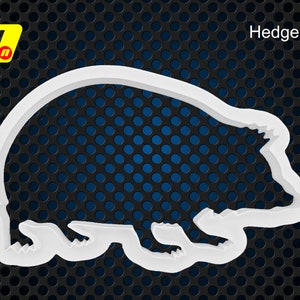 Könnte beinhalten: Weißer Plastik-Ausstecher in Form eines Igels. Der Ausstecher befindet sich auf einem schwarzen und blauen Hintergrund.