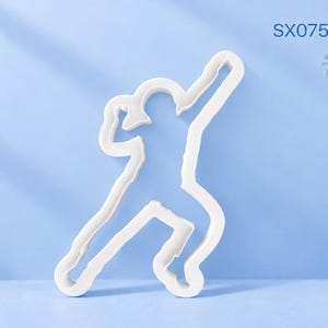 Pode incluir: Um cortador de biscoitos branco em forma de pessoa a escalar, com o texto SX075 Rock Climber. O cortador tem um contorno sólido e limpo, concebido para cortar massa na silhueta de um escalador que estende um braço para cima.