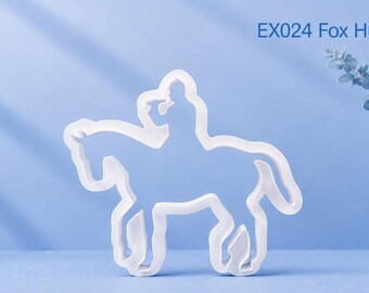 Puede incluir: Un cortador de galletas blanco con forma de persona montando a caballo, etiquetado como EX024 Fox Hunter. El contorno representa a un jinete a caballo en una vista de perfil clásica, con una construcción de plástico blanco sólido y definida.