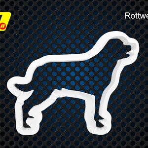 May include: White plastic cookie cutter shaped like a Rottweiler dog. The cookie cutter is on a black and blue background.