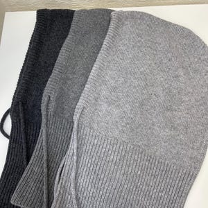 Puede incluir: Tres pasamonta&ntilde;as de punto en diferentes tonos de gris. Los pasamonta&ntilde;as tienen una textura acanalada y una corbata larga y fina en la parte inferior.