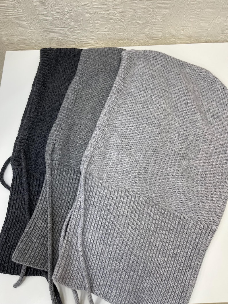 Puede incluir: Tres pasamonta&ntilde;as de punto en diferentes tonos de gris. Los pasamonta&ntilde;as tienen una textura acanalada y una corbata larga y fina en la parte inferior.