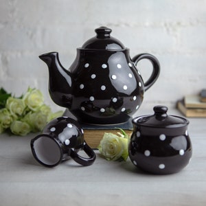 Può includere: Set da tè composto da teiera, zuccheriera e lattiera nera con pois bianchi. Il set è in ceramica e ha una finitura lucida.