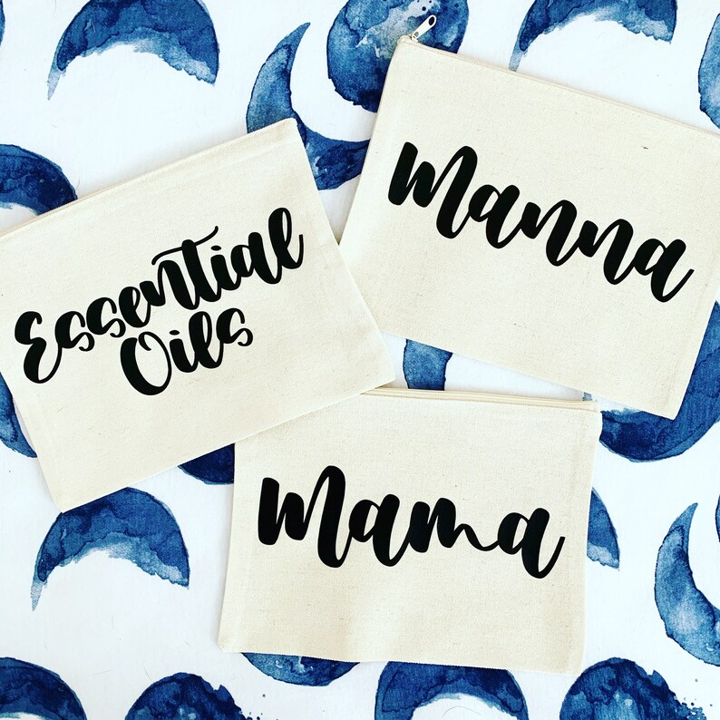 May include: Three off-white canvas zippered pouches with black text. The pouches are labeled "Essential Oils", "Mama", and "Manna".