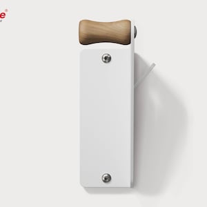 Peut inclure: Un porte-manteau mural blanc avec une poignée en bois et un crochet en métal. Le porte-manteau a une forme rectangulaire avec deux vis visibles. La marque "Rahle" est visible dans le coin supérieur gauche.