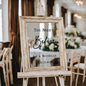 Puede incluir: Un letrero de madera r&uacute;stico con un inserto de vidrio transparente. El letrero dice "The Night Before" en una fuente cursiva, seguido de "Joy & Nicholas" y la fecha "12.23.2023".
