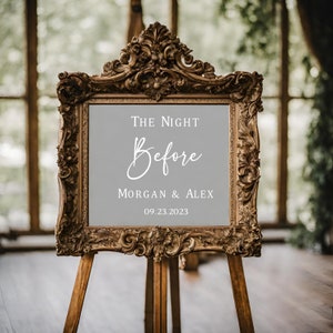 Puede incluir: Un marco dorado adornado con un fondo gris y texto blanco que dice "The Night Before Morgan & Alex 09.23.2023". El marco est&aacute; en un caballete de madera.