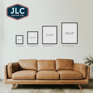 May include: Four black picture frames of different sizes on a white wall above a brown leather couch. The frames are labeled with their dimensions in inches and centimeters. The frames are 8x10 inches, 11x14 inches, 16x20 inches, and 18x24 inches.