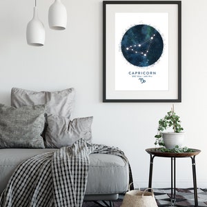 May include: A black framed print with a white background featuring a blue and white watercolour illustration of the Capricorn constellation with the text "CAPRICORN DEC 22nd - JAN 19th" and the Capricorn zodiac symbol.