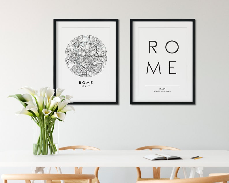 May include: Two black framed prints on a white wall. The print on the left shows a black and white map of Rome, Italy, in a circle. The print on the right shows the word "ROME" in black text with "ITALY" underneath.