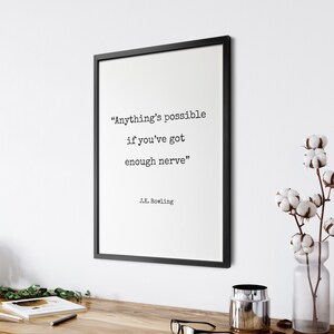 May include: Black framed print with a white background and the quote "Anything's possible if you've got enough nerve" by J.K. Rowling.