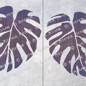 May include: Two purple monstera leaf stencils on a white textured background. The stencils are cut out of a thin material and are ready to be used for painting or crafting.