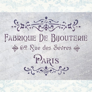 May include: A stencil design featuring the words "FABRIQUE DE BIJOUTERIE" and "PARIS" in a decorative font. The design includes floral and scroll accents, and the address "62 Rue des Sevres". The background is a textured, light grey.