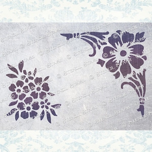 May include: Two floral stencils, one with a single large flower and the other with a cluster of smaller flowers. Both stencils are in a dark purple color on a light gray background.