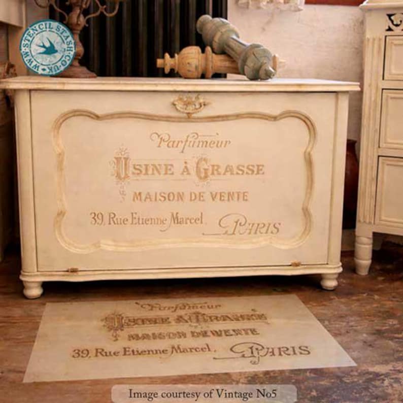 Może przedstawiać: Kremowa, antyczna skrzynia z pozłacanymi detalami i napisem "Parfumeur USINE &Agrave; GRASSE MAISON DE VENTE 39. Rue Etienne Marcel. PARIS." Na podłodze szablon z tym samym tekstem.