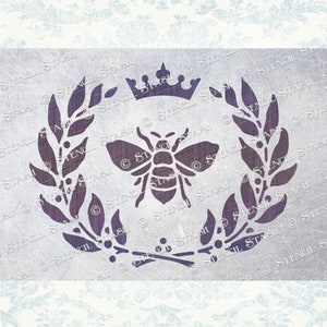 May include: A purple stencil design featuring a bee with wings, a crown, and a wreath of leaves. The stencil is on a light grey background.