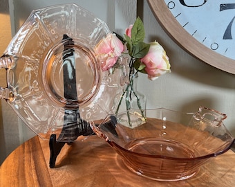 Op de afbeelding: Twee vintage glazen serveerschalen met handvatten. De grotere schaal is van helder glas met een gegolfde rand en de kleinere schaal is van roze glas met een gegolfde rand.