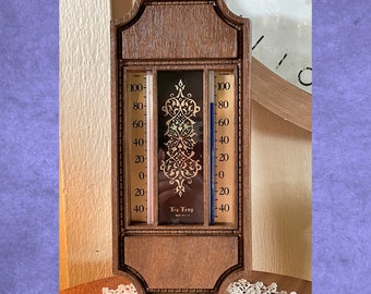 May include: A wooden framed indoor/outdoor thermometer with a gold-colored design. The thermometer has two scales, one for Fahrenheit and one for Celsius. The thermometer reads "Tru Temp" in the center.
