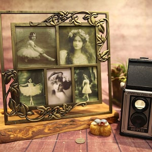 Puede incluir: Un marco de fotos vintage de latón con detalles florales ornamentados contiene cinco fotografías en blanco y negro de mujeres jóvenes. El marco está sobre un soporte de madera y una pequeña cámara está en primer plano.