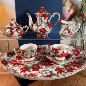 Puede incluir: Un juego de tres tazas de cerámica con un esmalte moteado de color crema. Cada taza presenta un diseño floral pintado a mano diferente en tonos azules, verdes y amarillos. Las tazas tienen una forma simple y moderna.