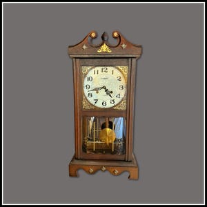 May include: A wooden antique clock with a decorative top and a pendulum visible through a glass door. The clock face has Roman numerals and ornate gold detailing. The clock is brown with gold accents.