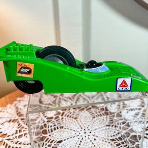 Puede incluir: Un coche de carreras de juguete verde con ruedas negras y un logotipo de Citgo. El coche tiene una pegatina que dice "Mini SSP by Kenner".