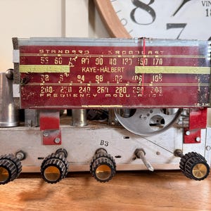 Puede incluir: Una taza de cerámica blanca con un asa negra y el texto "But First, Coffee" en negro y negrita. La taza está sobre una superficie de madera.