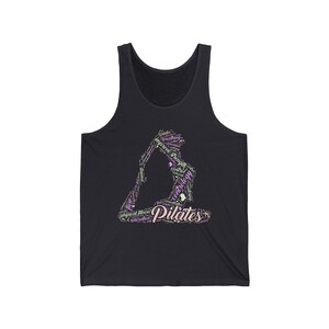Puede incluir: Camiseta sin mangas negra con un dise&ntilde;o tem&aacute;tico de Pilates. El gr&aacute;fico representa una figura en una postura de yoga, formada por palabras como "Pilates", "fuerza" y "control" en rosa y blanco. La camiseta sin mangas est&aacute; hecha de un material suave y c&oacute;modo.