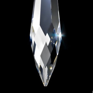 May include: A clear crystal teardrop pendant with a faceted design. The pendant has a hole at the top for hanging.