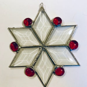 May include: A white glass snowflake ornament with a silver metal frame and six red glass beads.