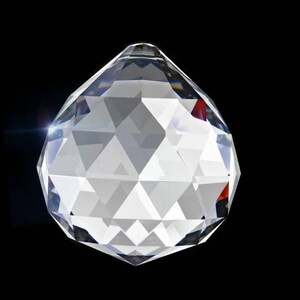 May include: A clear crystal ball with a faceted design. The ball is round and has a smooth, polished surface.