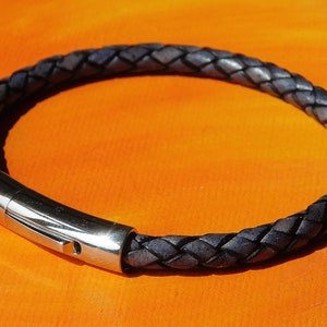 May include: A dark blue leather bracelet with a silver clasp.
