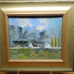 May include: An oil painting in a wide gold frame depicting a landscape with a white building, tall yellow trees, and a dark green tree under a blue sky with clouds. The foreground features a field with green and brown tones and a dark fence line.