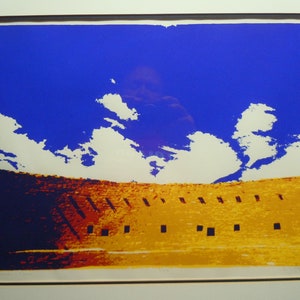 May include: A colorful abstract print of a building with a blue sky and white clouds. The building is a yellow-orange color with dark blue accents and has a row of windows.
