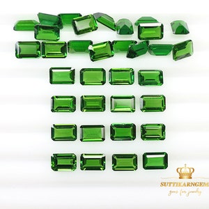 May include: A collection of vibrant green gemstones, cut into various rectangular and geometric shapes. The gems are arranged on a white surface, showcasing their clarity and color. The image highlights the facets and brilliance of the stones, perfect for jewelry making.