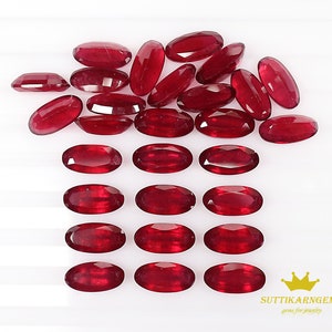 Puede incluir: Una colección de 20 piedras preciosas ovaladas de color rojo. Las piedras preciosas están dispuestas en un patrón, con algunas superpuestas. Las piedras preciosas son todas de tamaño y forma aproximadamente iguales.