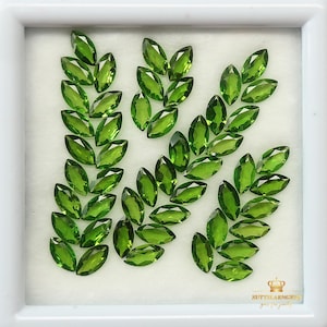 May include: A collection of 30 marquise-shaped green gemstones arranged in a leaf pattern. The gemstones are displayed in a white box with a white background.