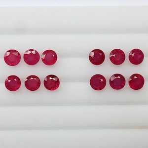 Może przedstawiać: Zestaw dziesięciu okrągłych, czerwonych kamieni szlachetnych, ułożonych w cztery rzędy po dwa lub trzy kamienie. Kamienie są oznaczone numerami od 1 do 4.