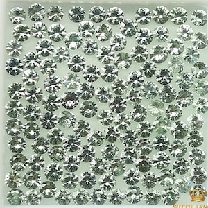 May include: A close-up view of a collection of round, faceted, green gemstones. The gemstones are arranged in a grid pattern on a white background.