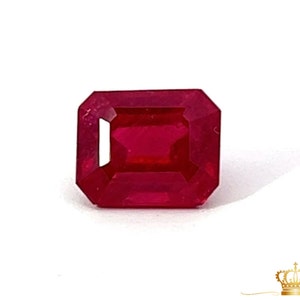 May include: A deep red emerald cut gemstone.