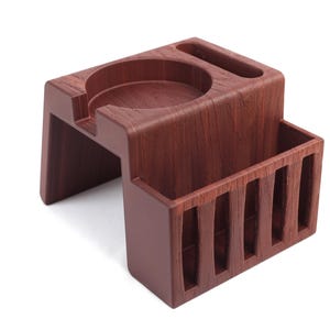 May include: A wooden espresso coffee station in a rich, dark brown color. The station features a circular indentation, a rectangular slot, and a slotted compartment. The design is modern and minimalist, suitable for home or office use.