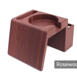 Puede incluir: Soporte de madera color palisandro con una hendidura circular y una ranura rectangular. El soporte tiene un dise&ntilde;o moderno con una base robusta y un peque&ntilde;o compartimento lateral. La palabra "Rosewood" se muestra en un rect&aacute;ngulo gris.