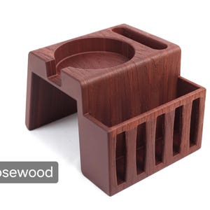 Puede incluir: Accesorio para m&aacute;quina de espresso de madera de palisandro. Este soporte de madera presenta una hendidura circular para un portafiltro, una ranura peque&ntilde;a y un compartimento rectangular con ranuras verticales. El soporte es de palisandro.