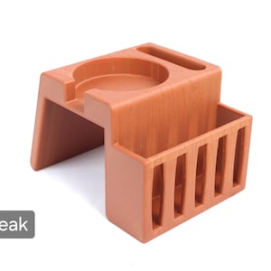 Puede incluir: Un organizador de escritorio de madera color teca con un soporte circular, una ranura y un compartimento rectangular con listones verticales. El organizador est&aacute; dise&ntilde;ado para guardar varios art&iacute;culos de escritorio.