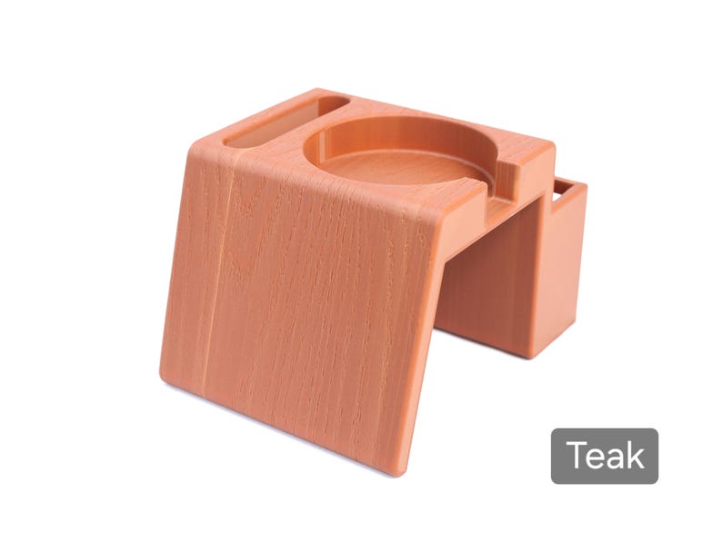 Puede incluir: Un organizador de escritorio color teca con un portavasos circular, una peque&ntilde;a ranura rectangular y un compartimento lateral. El organizador tiene un aspecto de veta de madera texturizada y est&aacute; etiquetado como "Teca".