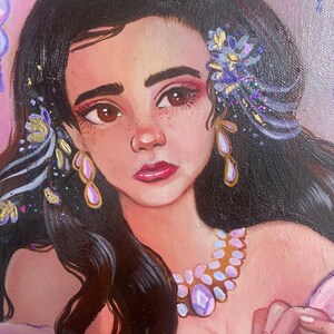 May include: A painting of a woman with long dark hair, wearing a white dress with a gold and purple necklace. She has a flower in her hair and is holding a small, round object.